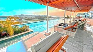 A poolside area with lounge chairs and a view of the ocean.