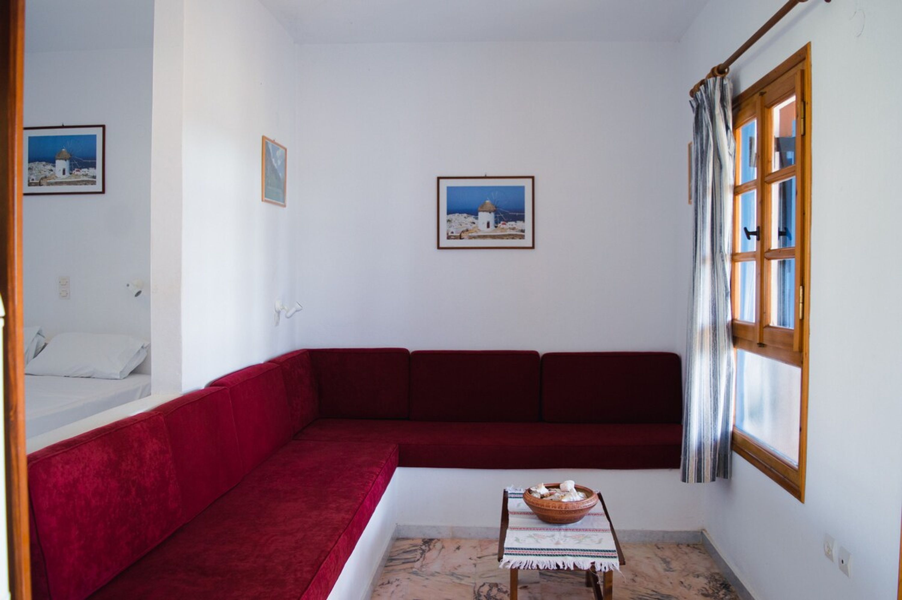 Una stanza con un divano rosso, un tavolino con una ciotola e due quadri appesi al muro.