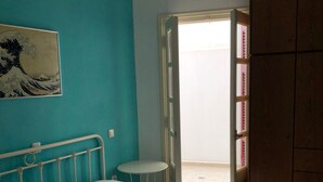 Un dormitorio con cama, almohadas, una mesita redonda y un cuadro en la pared.