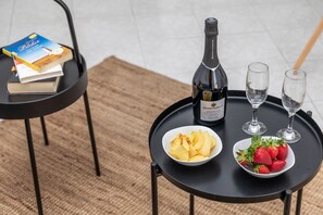 A table with a bottle of champagne, two glasses, a bowl of chips, a bowl of strawberries, and a book. - Manouk s - Two Bedroom Apartment (Naxos)