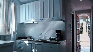 A modern kitchen with white cabinets, a black countertop, and a coffee maker. - Tsikalario Holiday House (Naxos)