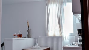 A small kitchen with a white countertop, a wooden table, and a window with curtains. - Tsikalario Holiday House (Naxos)