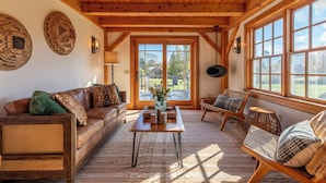 A cozy living room with a wooden ceiling, a large window, and a view of the outdoors.