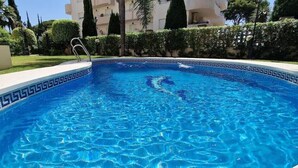 A swimming pool with a decorative border, surrounded by a well-maintained lawn and hedges. - weforyou Solymar 2 bedrooms (Benalmádena)