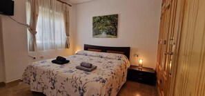 A bedroom with a bed, a painting, a bedside table, and a wardrobe.