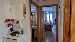 A narrow hallway leading to a bathroom with a sink and a mirror. - weforyou Solymar 2 bedrooms (Benalmádena)