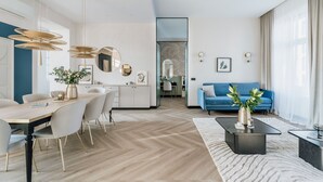 Una sala de estar moderna con un sofá azul, un comedor con mesa de madera y una cocina al fondo.