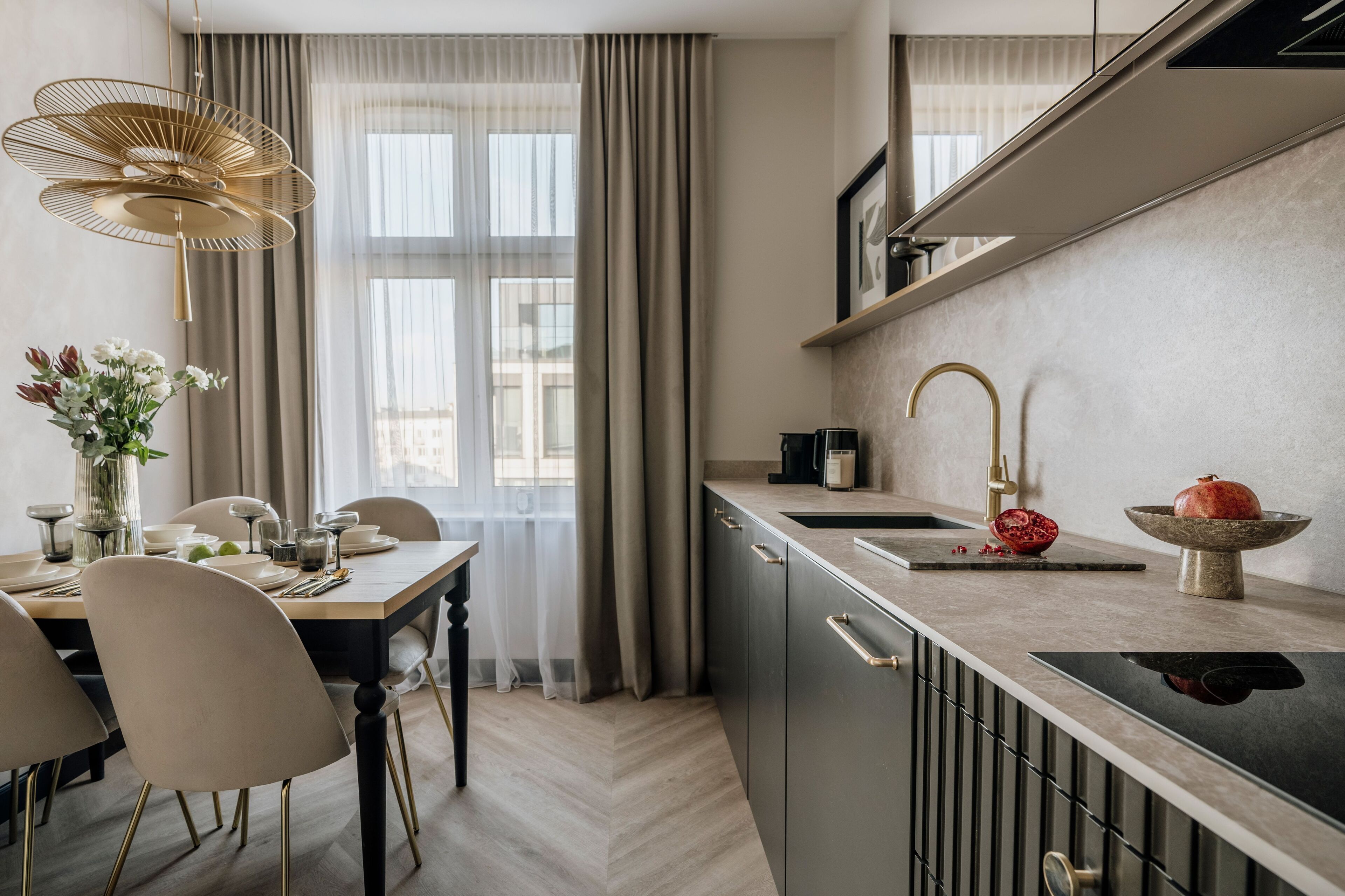 Una cocina moderna con zona de comedor, que cuenta con un ventanal grande, una lámpara colgante y una granada sobre la encimera.