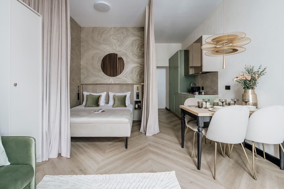 Une chambre d’hôtel moderne comprenant un lit, une table à manger avec des chaises et un coin cuisine.