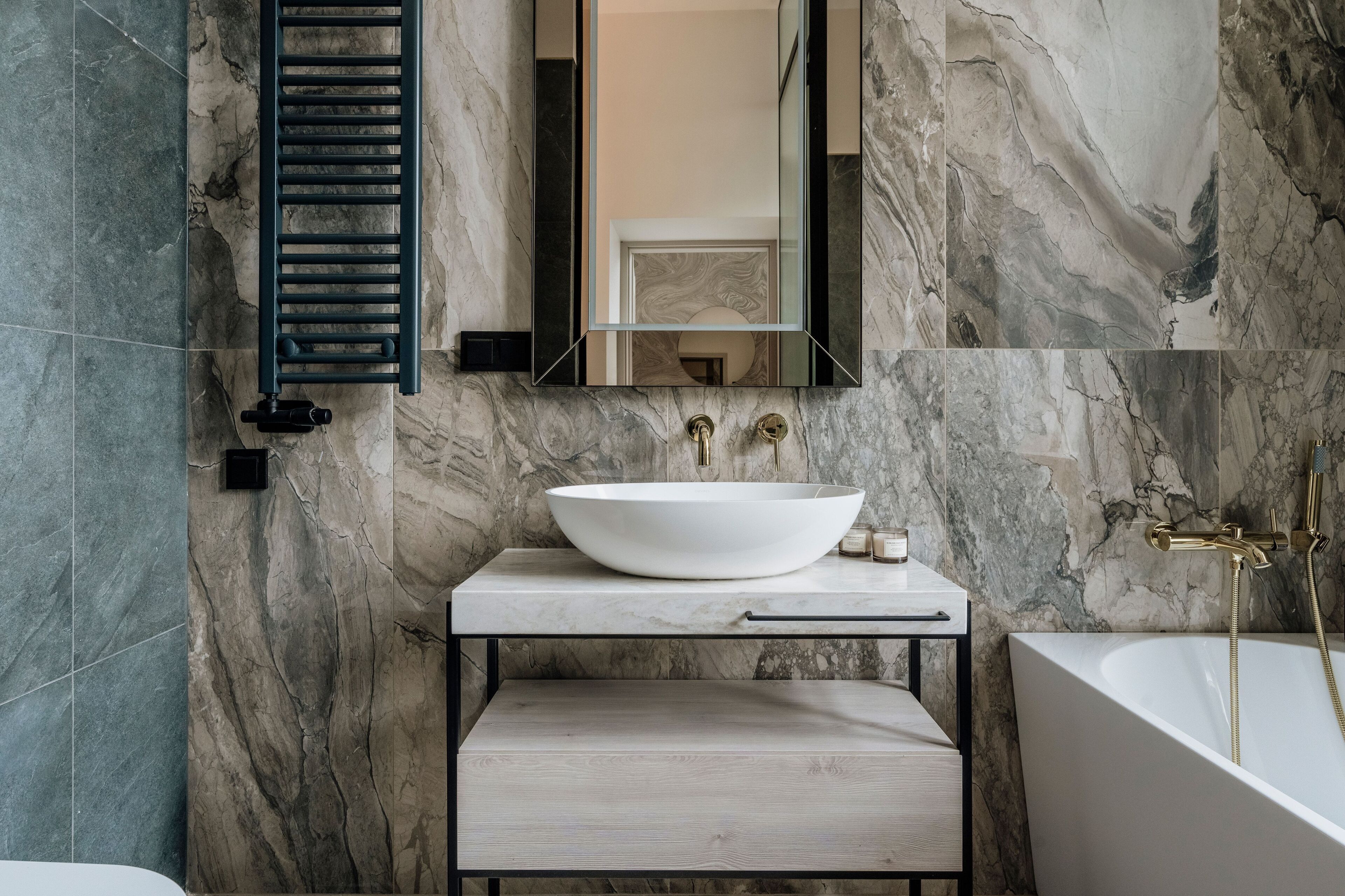 Une salle de bain dotée d’un grand lavabo sur pied de couleur blanche, d’une baignoire îlot et d’un miroir placé au-dessus du lavabo.