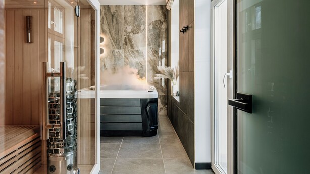 Un moderno espacio de spa con ducha de vapor, sauna y camilla de masaje.