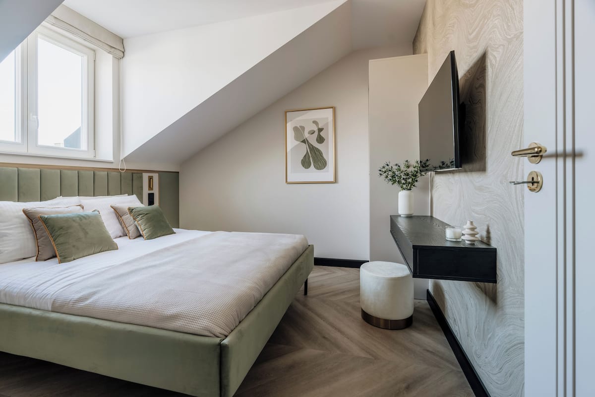 Une chambre à coucher moderne, avec un lit, une table de chevet, un téléviseur fixé au mur et une fenêtre.