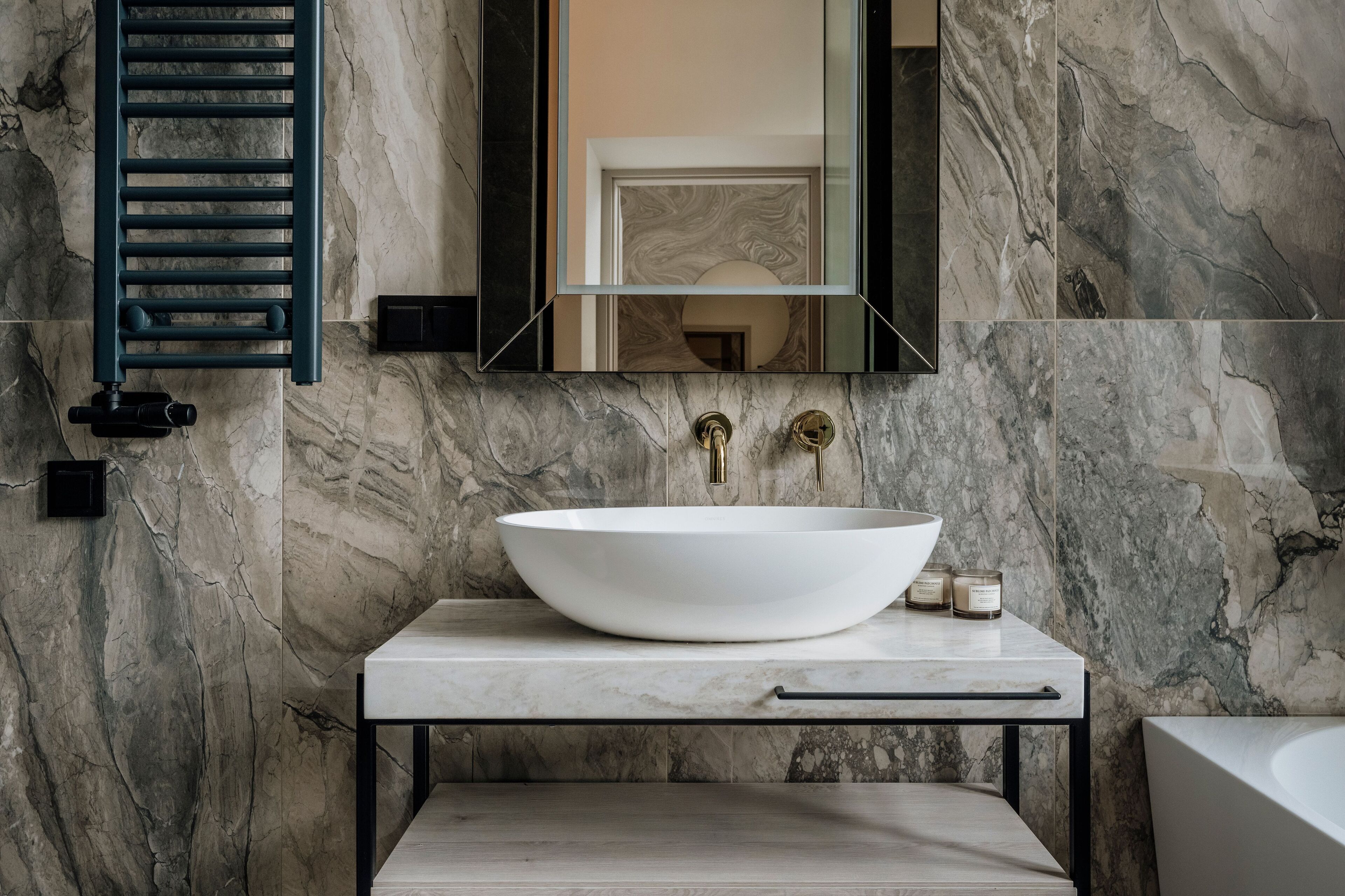 A bathroom with a large white vessel sink, a mirror, and a towel rack.