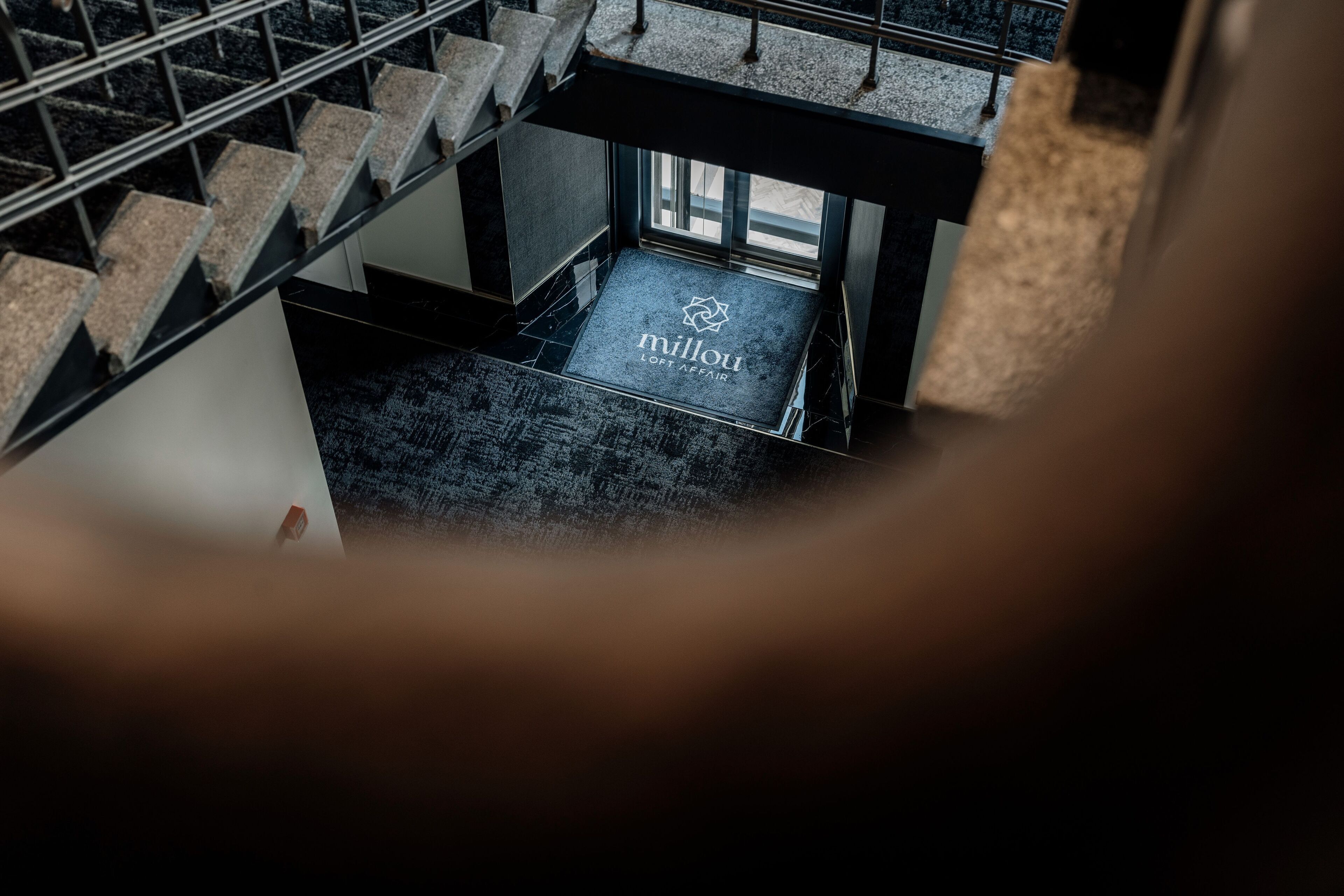 A staircase leading to a landing with a doormat that reads "millou lort affair."