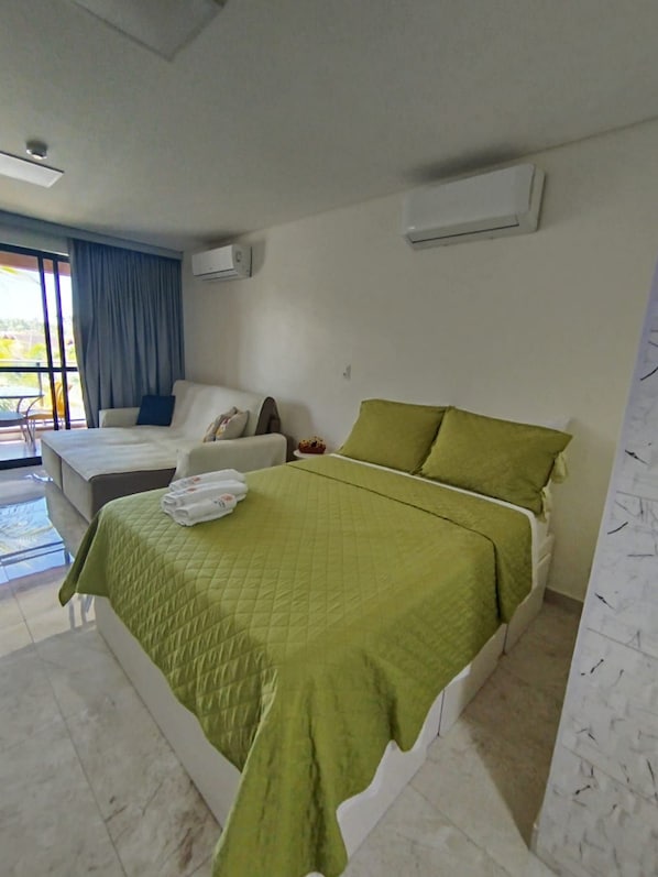 A hotel room with a bed, a sofa, a small table, and an air conditioning unit. - Eco Resort Praia dos Carneiros (Tamandaré)