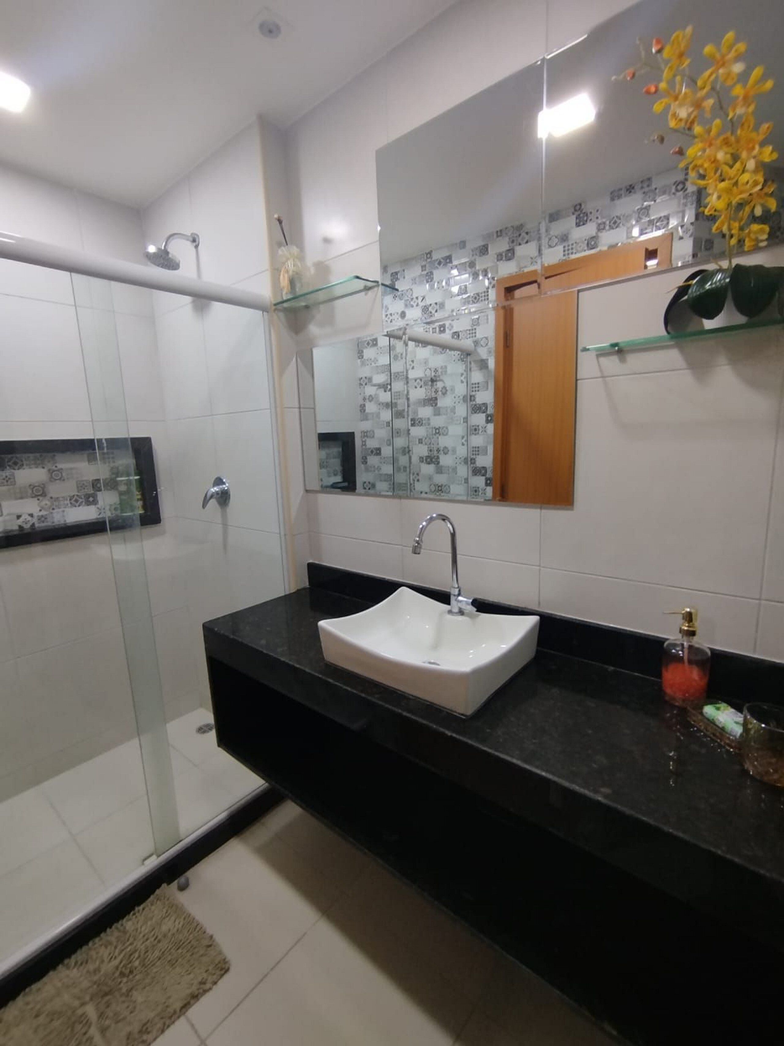 A modern bathroom with a glass shower enclosure, a white sink, and a mirror with a decorative backsplash.