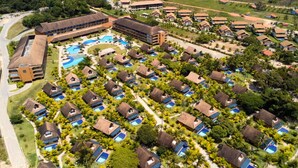An aerial view of a resort with multiple bungalow-style accommodations, a central swimming pool, and lush greenery. - Eco Resort Praia dos Carneiros  (Tamandaré)