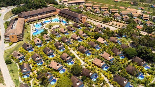An aerial view of a resort with multiple bungalow-style accommodations, a central swimming pool, and lush greenery. - Eco Resort Praia dos Carneiros  (Tamandaré)