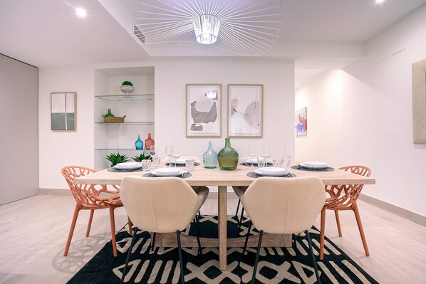 Un comedor moderno con mesa de madera, sillas naranjas y un tapete con estampado blanco y negro.