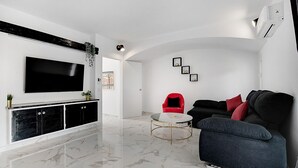 A modern living room with a flat-screen TV, a red chair, a black sofa, and a marble floor. - #266 Luxurious Villa Bellagio by Home Holidays (Albufeira)