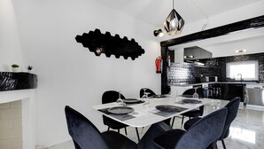 A modern dining area with a white table set for six, black chairs, and a black wall art piece. - #266 Luxurious Villa Bellagio by Home Holidays (Albufeira)