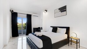 A modern bedroom with a large bed, a bedside table with a mirror, a chair, and a view of the outdoors. - #266 Luxurious Villa Bellagio by Home Holidays (Albufeira)