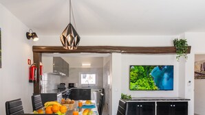 Una cocina moderna con comedor, televisor montado en la pared y extintor.