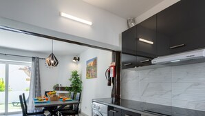 Una cocina moderna con armarios oscuros, un salpicadero de mármol y una zona de comedor con una mesa para dos.