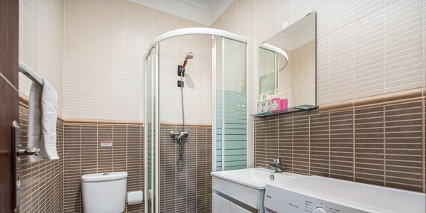 Een badkamer met een douche met glazen wand, een wit wastafelmeubel en een spiegel erboven.
