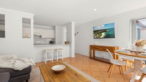 Una cocina moderna con armarios blancos, un comedor con mesa y sillas de madera, y un amplio ventanal con vistas panorámicas.