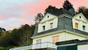 Un edificio de dos plantas con base de piedra y sección superior amarilla, con varias ventanas y un balcón.