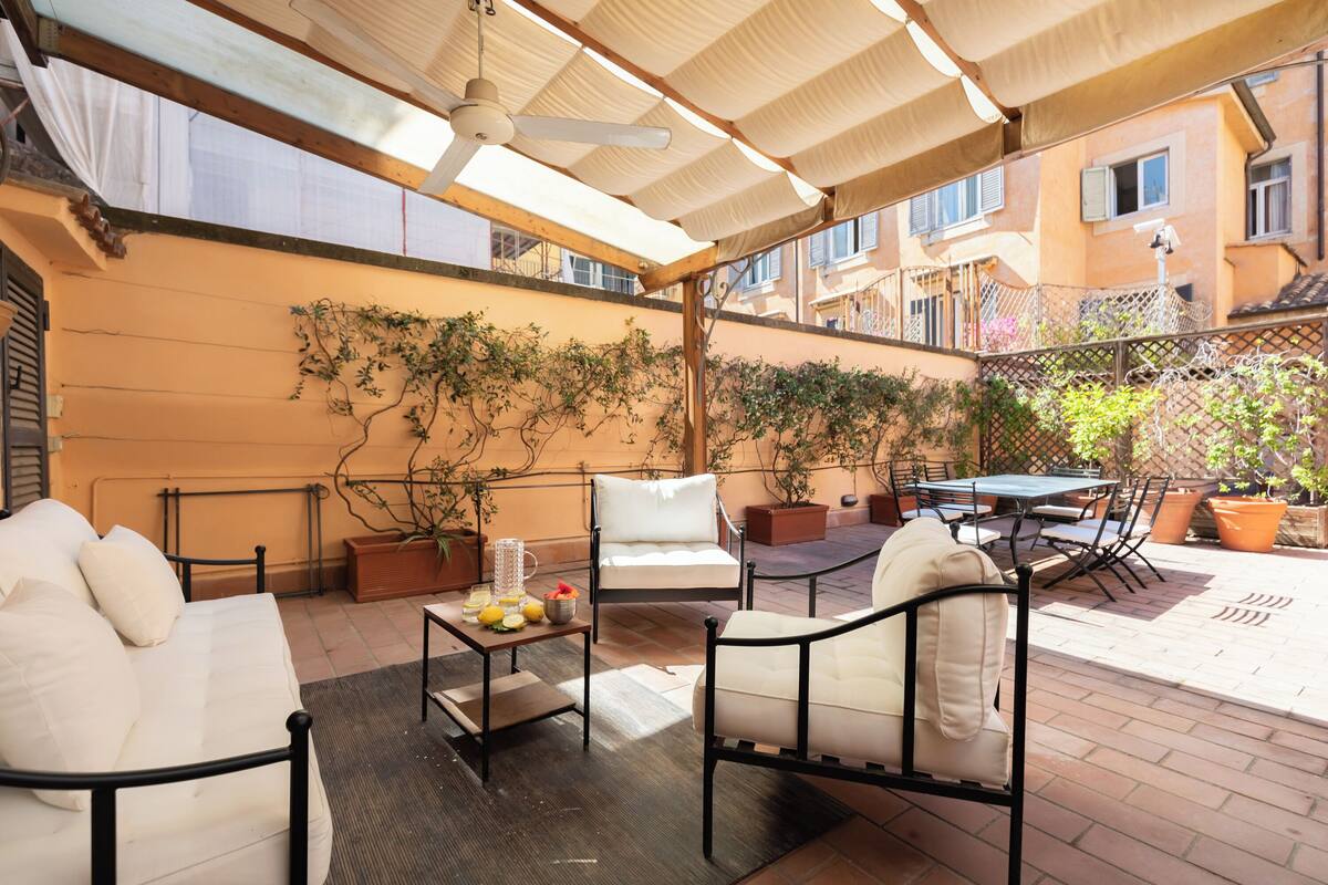Une terrasse extérieure avec une table et des chaises, un canapé et des plantes en pot.