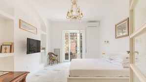 Une chambre à coucher avec un lit, une commode en bois, un téléviseur et un lustre.