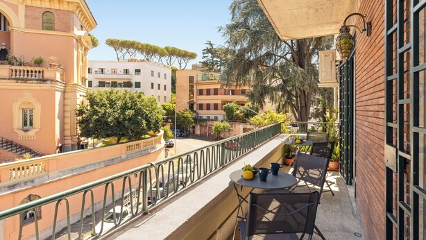 Un balcon avec une table, des chaises et des plantes en pot.