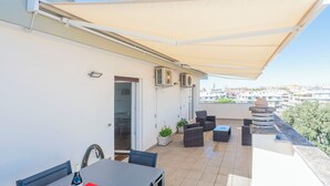 A balcony with outdoor furniture, a table, and a large canopy. - Caffarella Park Terraced 2Br Apartment (Rome)