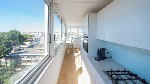 A modern kitchen with a large window, a view of the city, and a gas stove. - Caffarella Park Terraced 2Br Apartment (Rome)