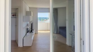 A modern apartment with a living area, a balcony with a city view, and a kitchen area. - Caffarella Park Terraced 2Br Apartment (Rome)