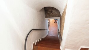 Eine schmale Treppe mit weißen Wänden und Terrakottafliesen.