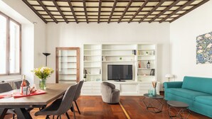 Een moderne woonkamer met een eethoek, houten vloeren, een bank en een televisie.