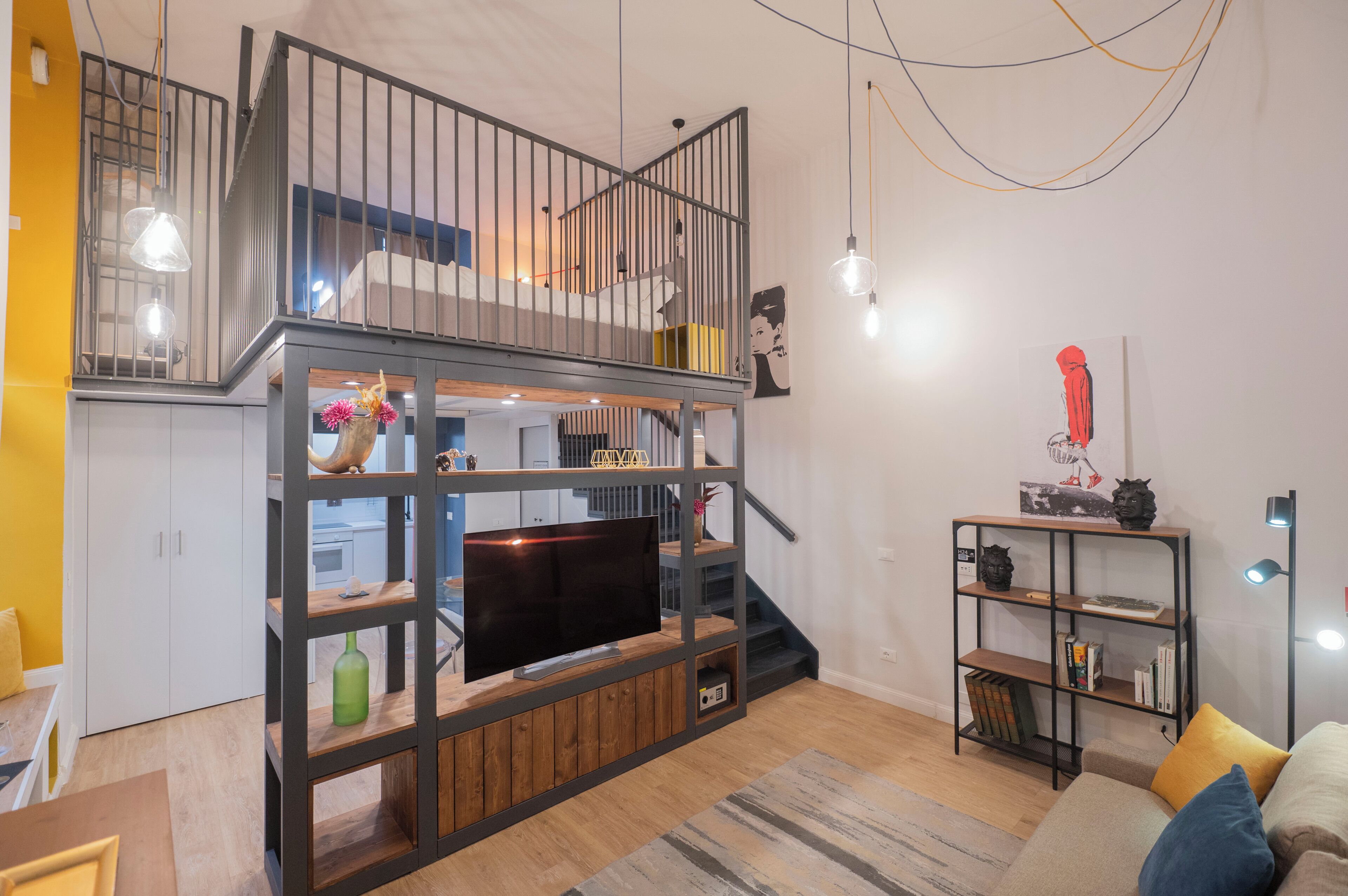 Ein moderner Wohnraum mit Fernseher auf einer Holz-Unterhaltungsanlage, einer Treppe und einem Bücherregal.