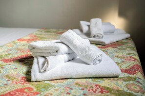 Toallas blancas dobladas con cuidado sobre una colcha estampada.