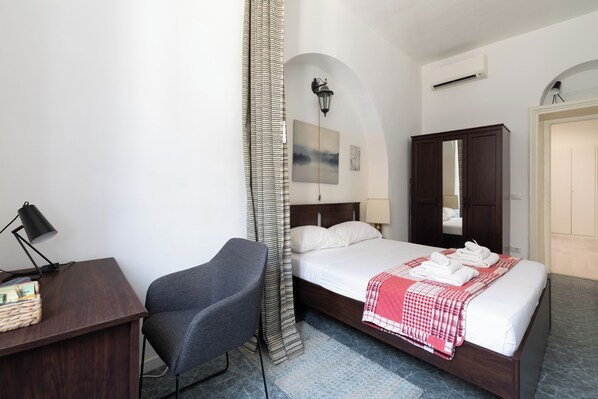 Una habitación de hotel con cama, escritorio, silla, armario y puerta de baño.
