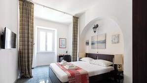 A hotel room with a large bed, a desk, a chair, and artwork on the walls. - Cozy And Comfy Apartment At Esquilino (Rome)