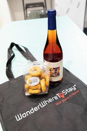 Una botella de vino y una bolsa de bocadillos sobre una mesa con un posavasos negro.