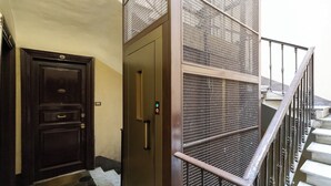 A hotel entrance with a dark wooden door, a metal gate, and a staircase with a metal railing. - Cozy And Comfy Apartment At Esquilino (Rome)
