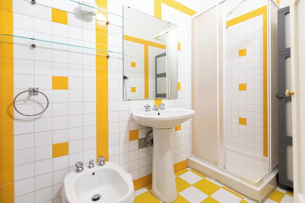 A bathroom with a white sink, a bidet, and a shower.