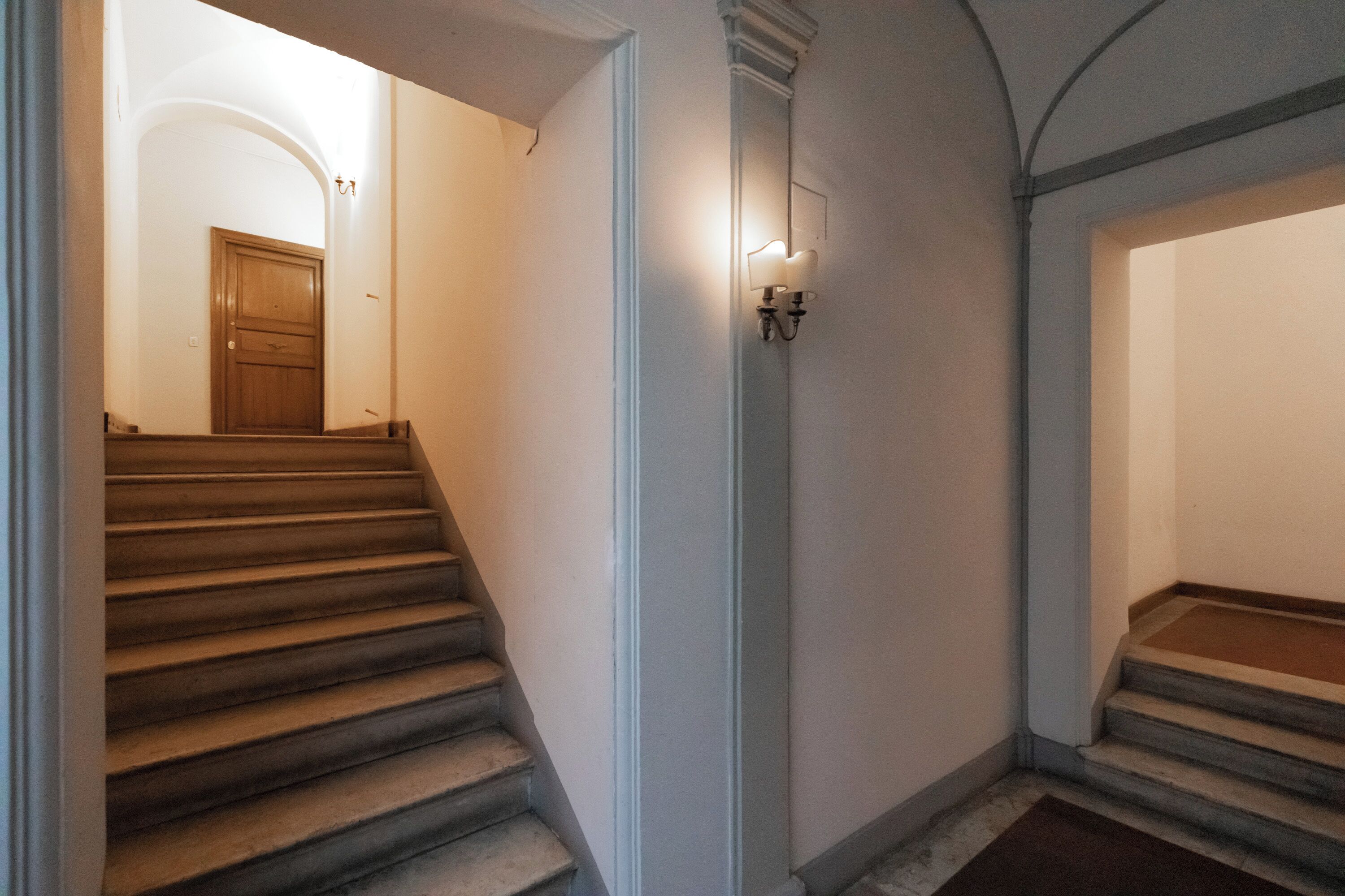 Una escalera con acabado de madera que lleva a una puerta en la parte superior.