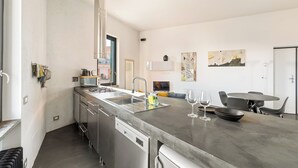 Una cocina moderna con electrodomésticos de acero inoxidable, lavavajillas y un comedor con mesa y sillas.