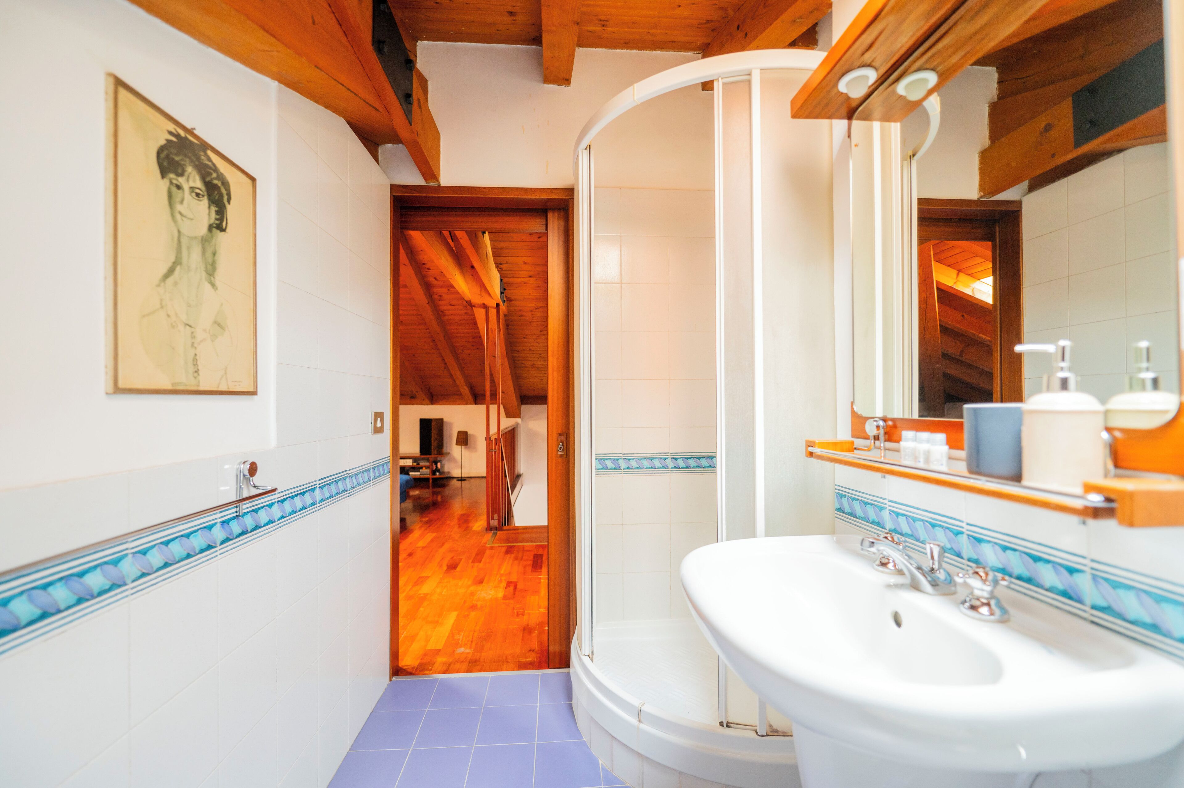 A bathroom with a white sink, a mirror, and a shower.