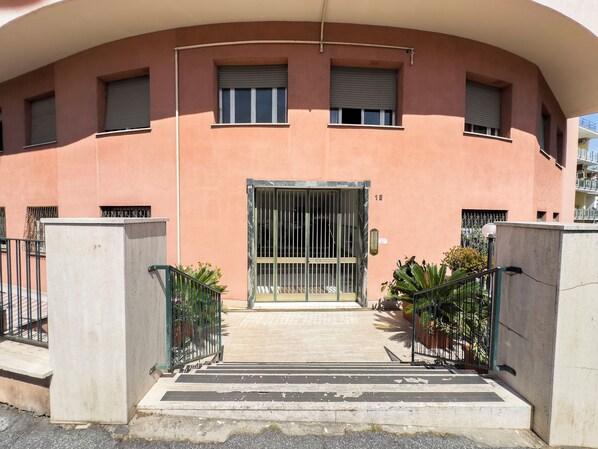 Un bâtiment doté d’une façade incurvée, d’une entrée protégée par un portail et d’un escalier menant à la porte.